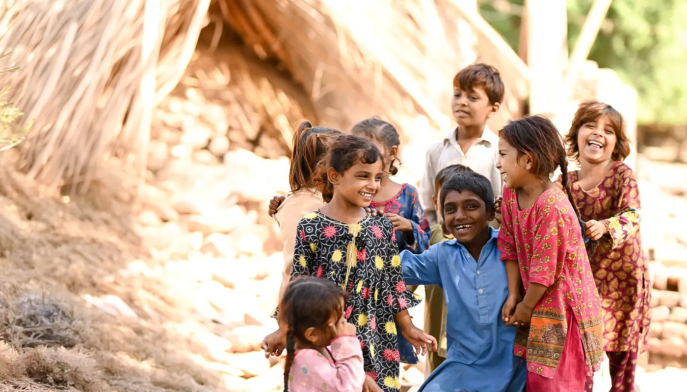 A group of laughing children smile at the camera.