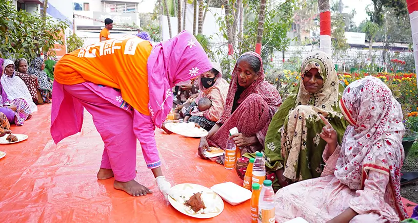 A group of women are served an iftar meal by a Penny Appeal worker.