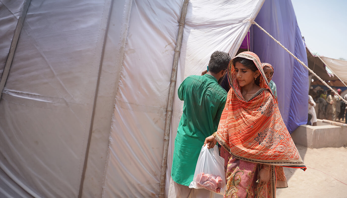 Qurbani donated by Penny Appeal donors being picked up by lady at distribution tent in Pakistan.