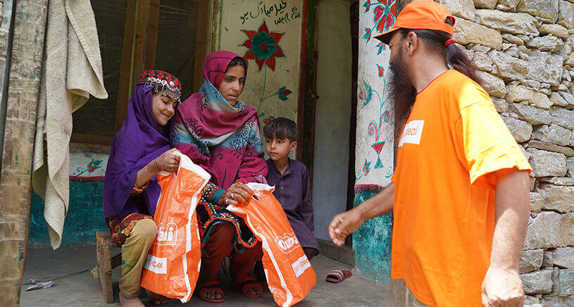 A Penny Appeal worker hands Qurbani bags to a family.