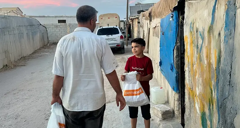 A man and boy holding Penny Appeal bags.