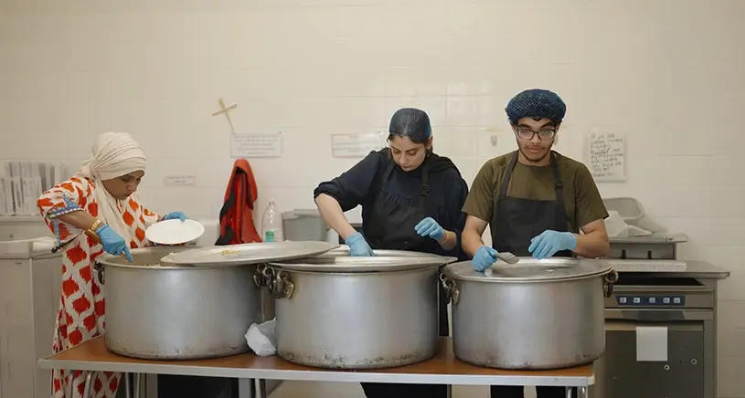 Penny Appeal workers cooking Qurbani meat in large pots.