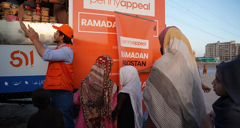 People queuing to receive food for a Penny Appeal food truck.