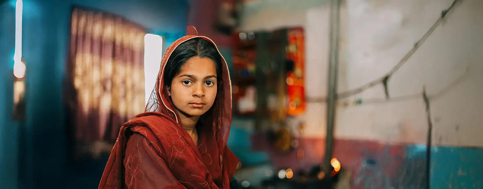 A girl in red traditional dress looks directly at the camera.