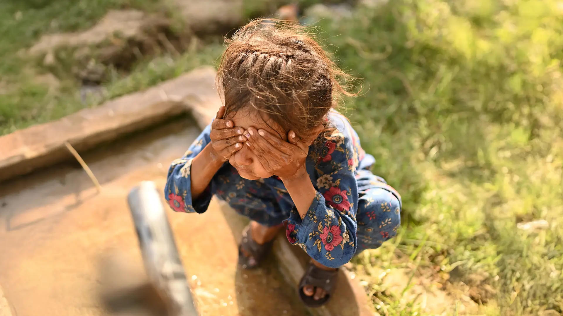 A little girl washes her face near a tube well installed through Penny Appeal’s Thirst Relief program, bringing fresh water to her community.