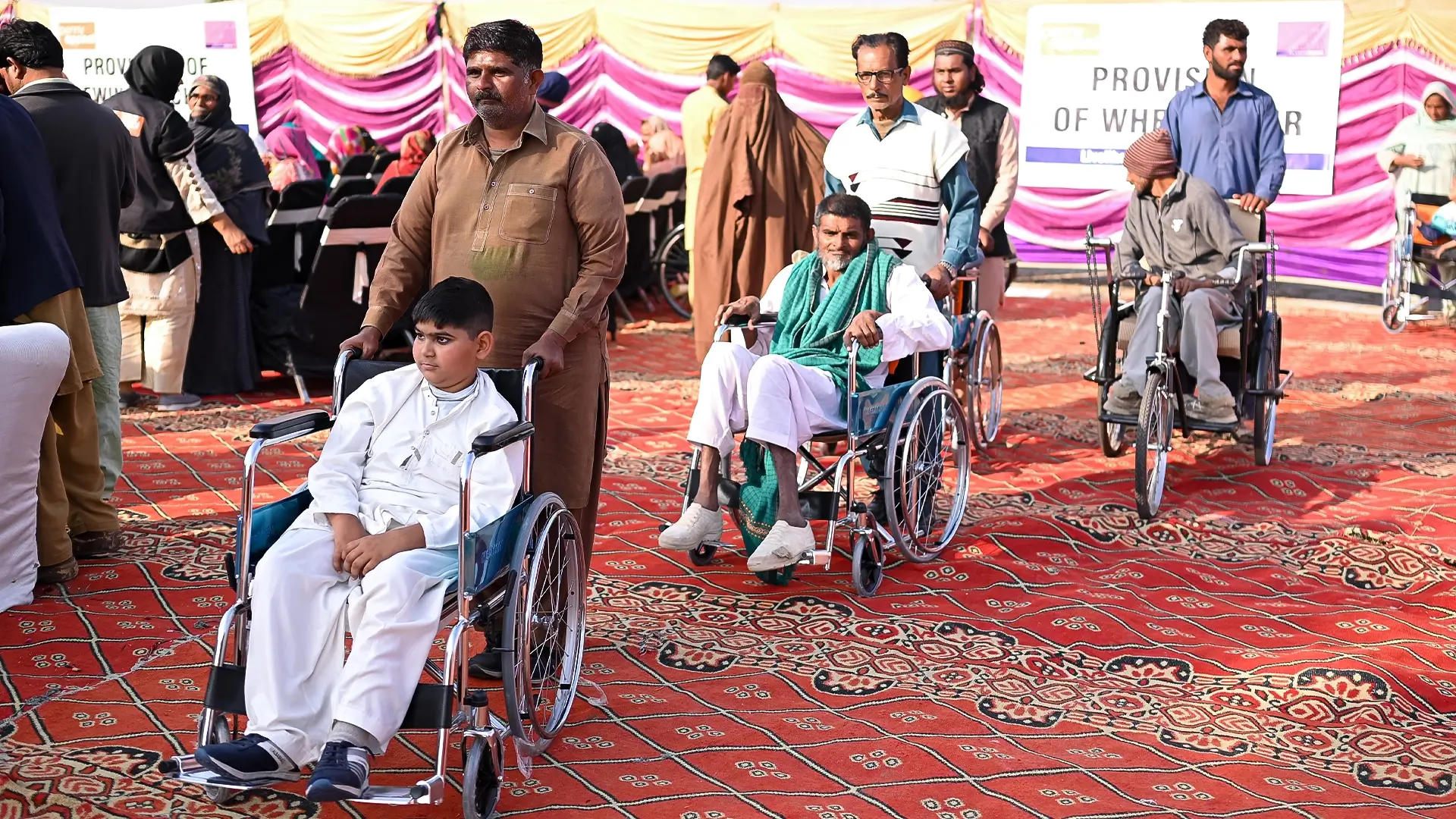 3 men push friends on family members sat in wheelchairs.