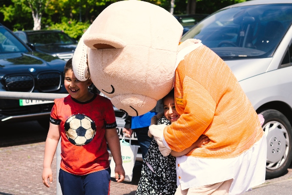 Penny the prayer bear hugging a child