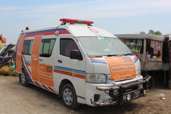 Van with 'free medical care' banner across the front and sides.